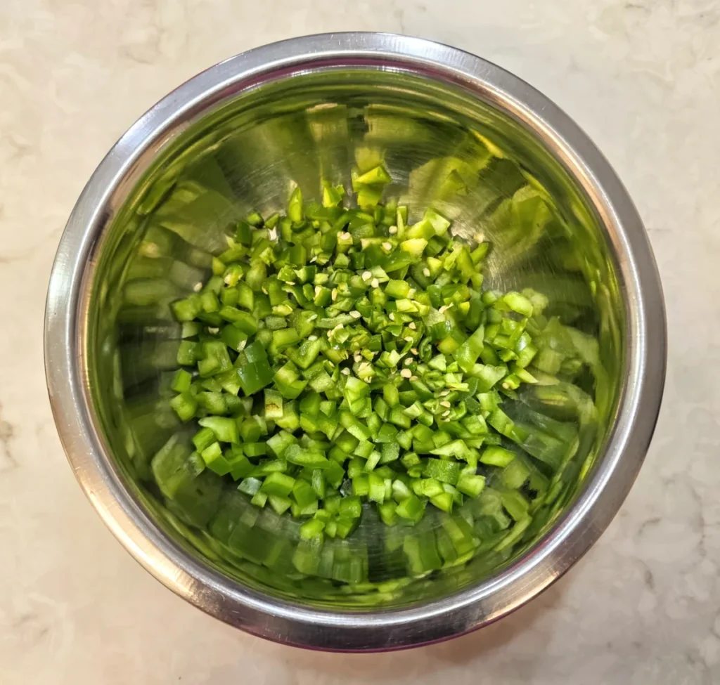 Finely chopped green capsicum in a mixing bowl.