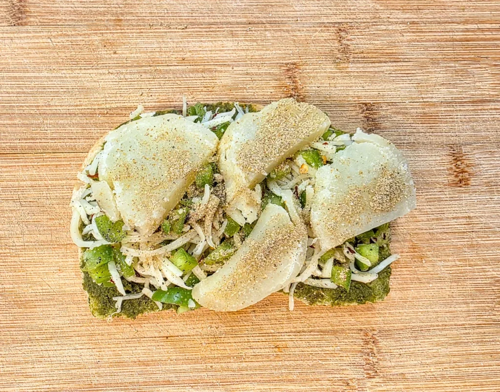 Boiled potato slices layered over the filling and sprinkled with chaat masala.