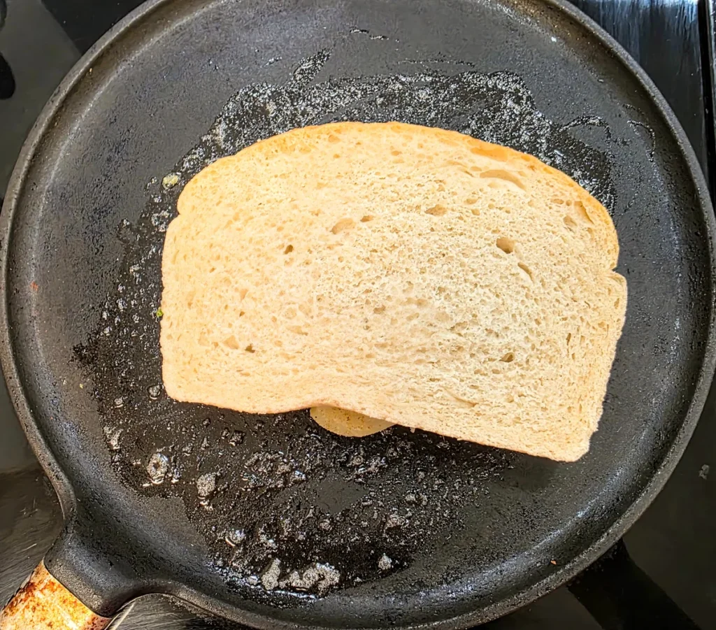 Buttered sandwich toasting in a hot grill pan.