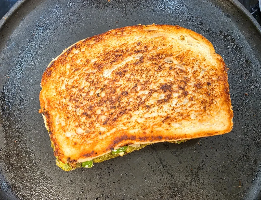 Toasted sandwich with golden grill marks lifted out of the pan.